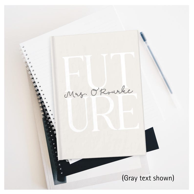 May include: A light beige notebook with the word "FUTURE" in large white letters and "Mrs. O'Rourke" in cursive. The notebook is on top of other notebooks and a pen.
