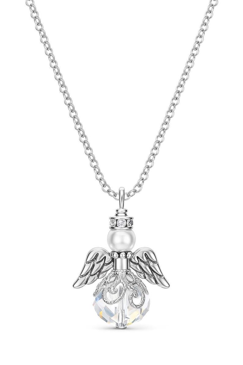 May include: A silver-toned necklace featuring an angel pendant. The pendant has a pearl head, crystal body, and detailed wings. The chain is a delicate link style. The necklace is designed to be worn as a fashion accessory.
