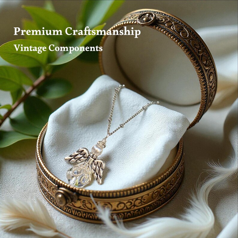 May include: A silver necklace with an angel pendant rests inside an open, ornate, gold-colored jewelry box. The angel pendant has crystal wings and a pearl-like bead. The box is lined with white fabric. Text on the image reads "Premium Craftsmanship Vintage Components."