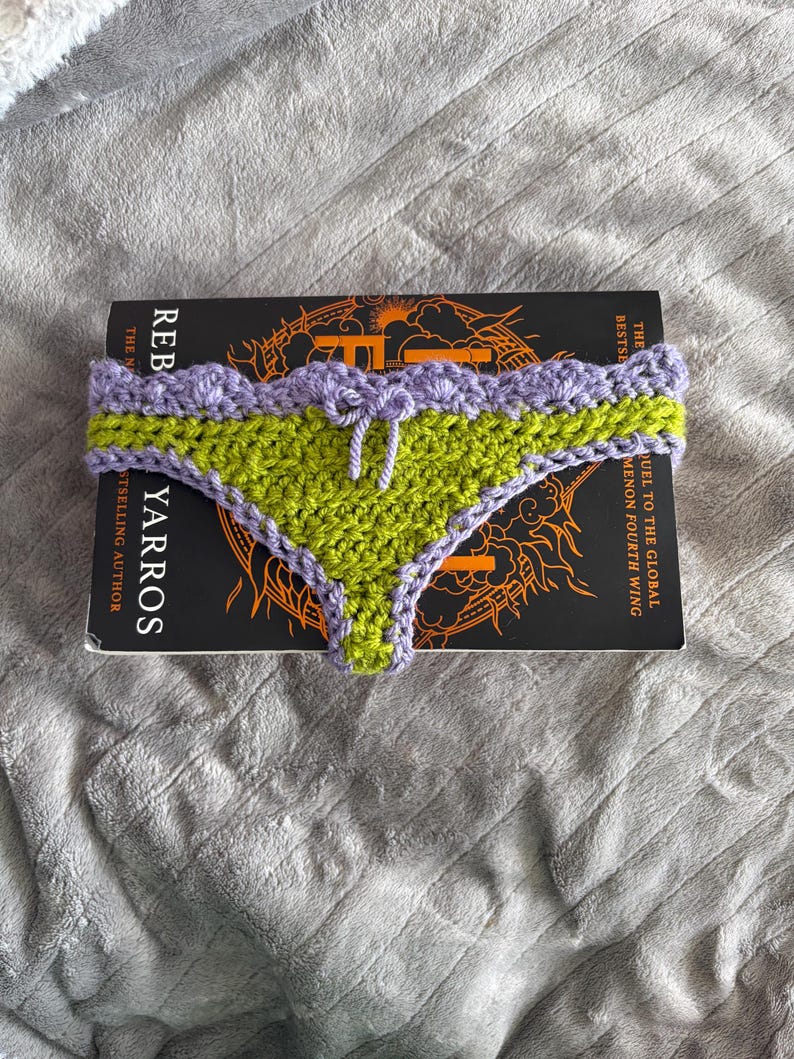 May include: A handmade crochet bikini bottom featuring a vibrant lime green center panel with a scalloped lavender trim along the waistband and leg openings. A small lavender crochet bow is centered at the front waistband of the garment.