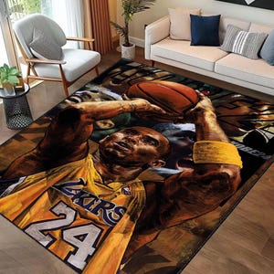 May include: A brown and yellow area rug with a basketball player in a yellow jersey with the number 24 on it. The player is holding a basketball and is in mid-air. The rug has a dark brown background with a faded look.
