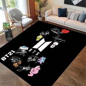 Peut inclure: Tapis noir et blanc avec le texte "BTS" et "BT21" en blanc. Le tapis présente une variété de personnages de dessins animés colorés, notamment un cœur rouge, un poussin jaune, un ours blanc et un lapin bleu.