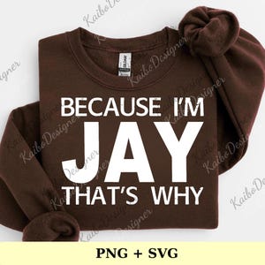 Puede incluir: Una sudadera marrón oscuro con el texto blanco "BECAUSE I'M JAY THAT'S WHY". La sudadera está doblada, con las mangas y la capucha visibles. La parte inferior de la imagen muestra "PNG + SVG".