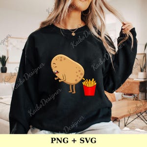 Op de afbeelding: Zwart sweatshirt met een cartoon aardappel en een rode frietbak. De aardappel heeft een grappige uitdrukking. De tekst "PNG + SVG" staat onderaan.
