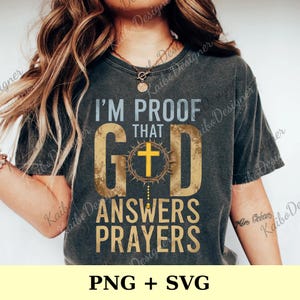 May include: Dark gray t-shirt with the text "I'M PROOF THAT GOD ANSWERS PRAYERS" in a distressed gold and white font. The word "GOD" features a cross within a crown of thorns. The bottom of the shirt reads "PNG + SVG".