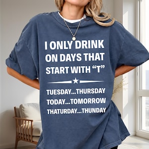 Può includere: Una t-shirt a maniche corte blu navy con testo bianco che recita: I ONLY DRINK ON DAYS THAT START WITH "T" TUESDAY...THURSDAY TODAY...TOMORROW THATURDAY...THUNDAY, con una piccola grafica a stella centrata tra le righe di testo.