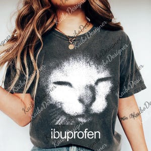A woman wearing a gray t-shirt with a cat image printed on it, posing against a white background.