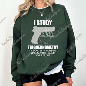 May include: Dark green sweatshirt with the text "I STUDY TRIGGERNOMETRY" and a graphic of a handgun with mathematical diagrams. The text "I'M GOOD WITH NUMBERS LIKE .40, 9 MM, .45 ACP, 5.56, 7.62, 308" is also printed on the sweatshirt.