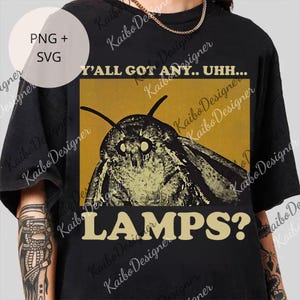 May include: Black t-shirt featuring a moth illustration with the text "Y'ALL GOT ANY.. UHH... LAMPS?". The design includes a moth with large eyes and antennae, set against a yellow background.