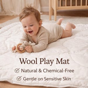Pode incluir: Um tapete de brincar de lã acolchoada branca com uma textura macia e padrões costurados. O texto no tapete diz: Wool Play Mat, Natural & Chemical-Free e Gentle on Sensitive Skin. O tapete foi concebido para o chão e oferece uma superfície.