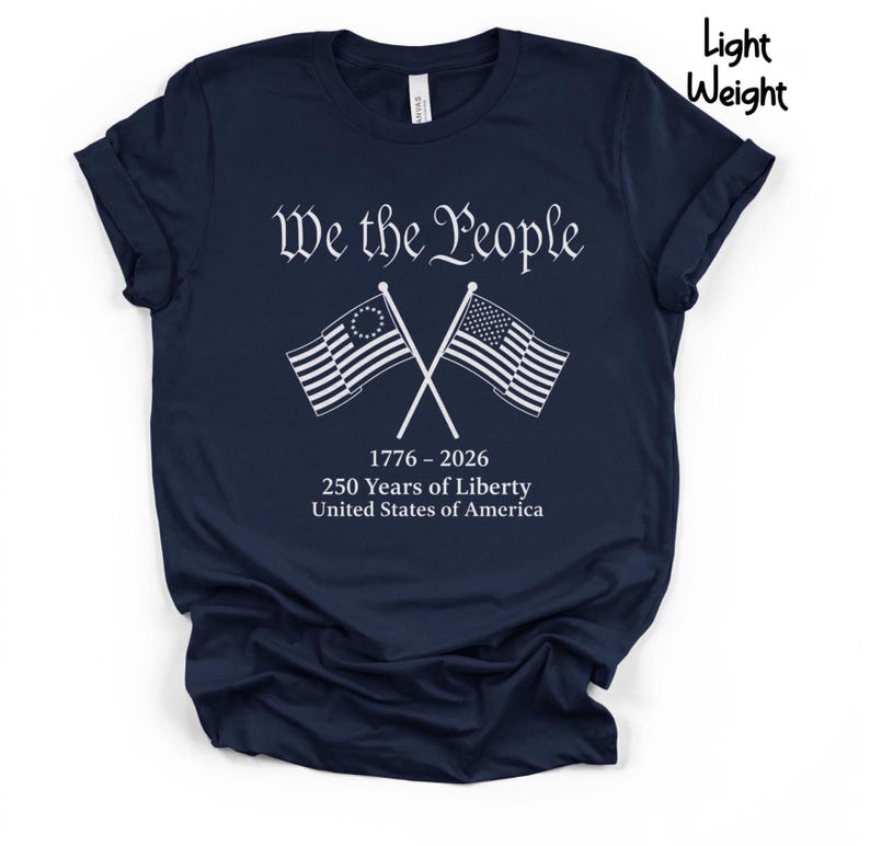 May include: Navy blue t-shirt with the text "We the People" in white script above crossed American flags. Below the flags are the dates "1776-2026" and the text "250 Years of Liberty United States of America."