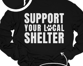 May include: Black long-sleeve shirt with the text "SUPPORT YOUR LOCAL SHELTER" in white. A paw print graphic is included. The front left pocket area has a custom shelter name option. The back design is also shown.