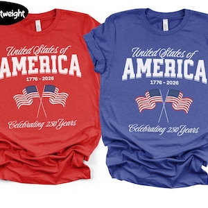 Puede incluir: Dos camisetas, una roja y otra azul, con el texto "United States of America 1776-2026 Celebrating 250 Years". Cada camiseta presenta dos banderas americanas. Las camisetas son ligeras.