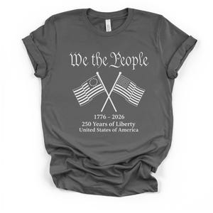 May include: Dark gray t-shirt with the text "We the People" above crossed American flags. The flags are white with blue and red accents. Below the flags is the text "1776-2026 250 Years of Liberty United States of America."