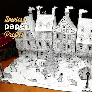 Puede incluir: Diorama de papel en blanco y negro de una escena de pueblo invernal. El diorama presenta varios edificios, una pista de patinaje, un árbol de Navidad y figuras de personas patinando. El texto "Timeless paper Project" es visible.