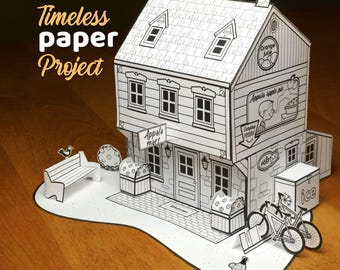 Puede incluir: Un modelo de papel en blanco y negro de un edificio de dos pisos etiquetado como Appala mart, que incluye un banco, bicicletas y una caja de hielo. El texto Timeless paper Project es visible a la izquierda. La estructura presenta ventanas detalladas, tejas y letreros para Orange Julie y Appala apple pie.