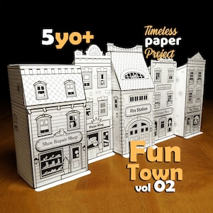 Puede incluir: Un conjunto de cinco edificios de papel blanco con ilustraciones de líneas negras, incluyendo un Shoe Repair Shop, Pizza King, Fire Station, Antique Shop y Pet Shop. El texto 5yo+, Timeless paper Project y Fun Town vol 02 está impreso en la imagen.