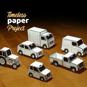 May include: A selection of white paper model vehicles, including a tractor, car, truck, van, and pickup truck, displayed on a wooden surface. The text "Timeless paper Project" is in the upper left corner.