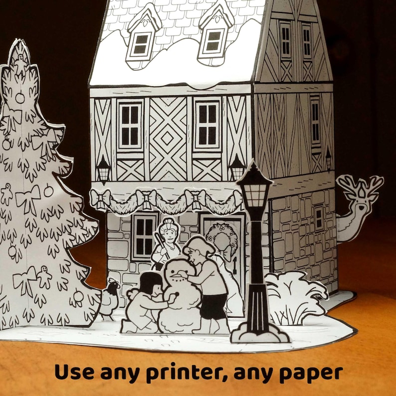 May include: A black and white paper craft set featuring a two-story house with a gabled roof, a decorated Christmas tree, a street lamp, and figures building a snowman. The text "Use any printer, any paper" is printed at the bottom.