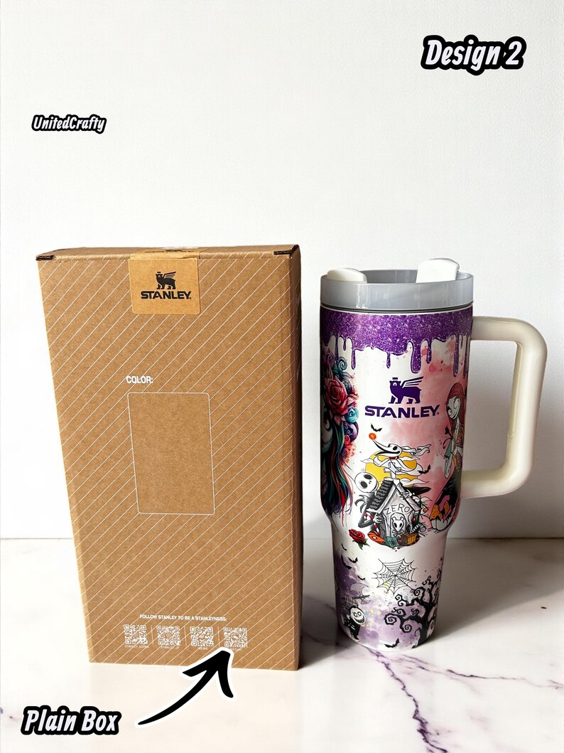 Puede incluir: Un vaso Stanley con asa y tapa blancas, con un dise&ntilde;o colorido con motivos de Halloween. El vaso est&aacute; junto a una caja marr&oacute;n lisa con el logotipo de Stanley.