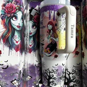 Puede incluir: Un vaso blanco con asa, con una colorida ilustraci&oacute;n de un personaje con puntadas y rosas, junto con una caja a juego. La caja y el vaso tienen un tema de Halloween con murci&eacute;lagos, telara&ntilde;as y &aacute;rboles. El asa tiene el nombre "Tamra".