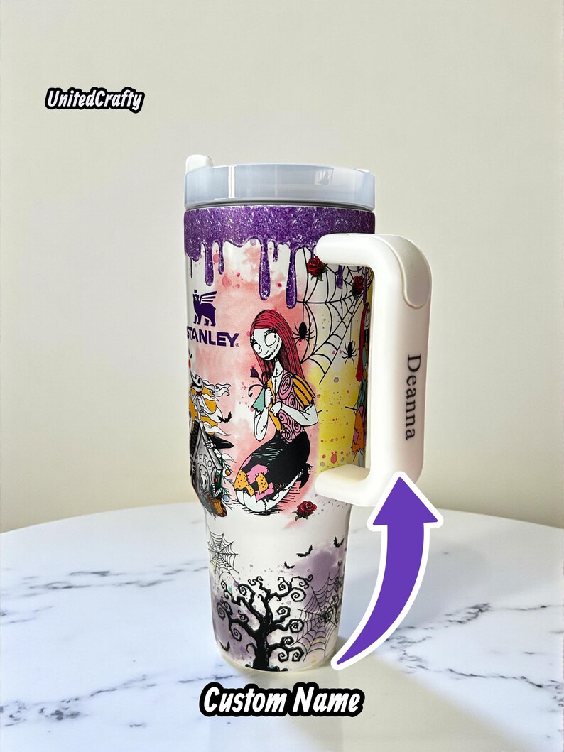 Puede incluir: Un vaso Stanley personalizado con un dise&ntilde;o de Sally de Pesadilla antes de Navidad. El vaso tiene un asa blanca con el nombre "Deanna" y las palabras "Custom Name" en la parte inferior. El borde superior es morado con purpurina.