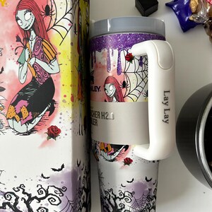 Puede incluir: Un vaso de acero inoxidable con asa blanca y caja a juego. El vaso presenta un dise&ntilde;o de Sally de Pesadilla antes de Navidad, con telara&ntilde;as, rosas y murci&eacute;lagos. La caja tiene un dise&ntilde;o similar.
