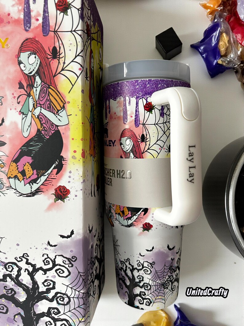 Puede incluir: Un vaso de acero inoxidable con asa blanca y caja a juego. El vaso presenta un dise&ntilde;o de Sally de Pesadilla antes de Navidad, con telara&ntilde;as, rosas y murci&eacute;lagos. La caja tiene un dise&ntilde;o similar.