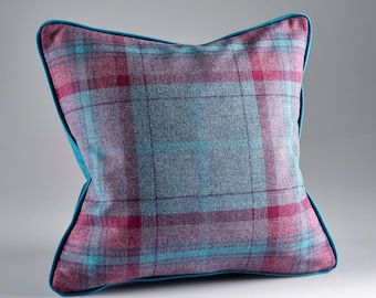 Könnte beinhalten: Quadratisches Kissen mit einem Karomuster in Grau-, Türkis- und Magentatönen. Das Kissen hat einen türkisfarbenen Rand und misst ca. 40 cm x 40 cm, ideal für die Inneneinrichtung.