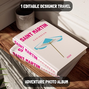 Pode incluir: Um álbum de fotos branco com um título rosa "SAINT MARTIN CARIBBEAN" e uma ilustração de um guarda-chuva azul e branco. O álbum é rotulado como "ALBUM DE FOTOS DE AVENTURA" e o ano "2024" está impresso na capa.