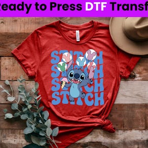 Puede incluir: Camiseta roja con un personaje azul Stitch sosteniendo un cono de helado. La camiseta tiene el texto "Stitch" escrito en letras azules.