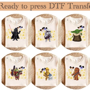 May include: Six white t-shirts with different Star Wars characters printed on them. The characters include Darth Vader, a Stormtrooper, Yoda, Boba Fett, C-3PO, and Chewbacca. The shirts are ready to be pressed with a DTF transfer.