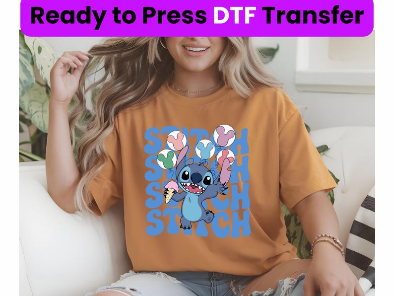 Puede incluir: Una mujer lleva una camiseta amarilla mostaza con un gr&aacute;fico azul de Stitch y el texto "Stitch" repetido en azul. El gr&aacute;fico muestra a Stitch sosteniendo un cono de helado rosa y blanco y rodeado de globos de colores.