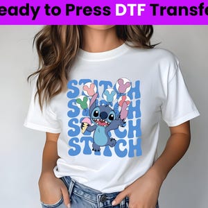 Puede incluir: Camiseta blanca con un personaje azul Stitch sosteniendo un cono de helado. El dise&ntilde;o presenta la palabra "Stitch" repetida en una fuente retro con globos de colores.