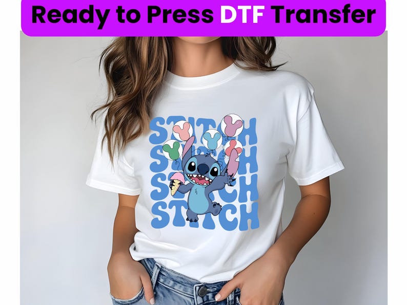 Puede incluir: Camiseta blanca con un personaje azul Stitch sosteniendo un cono de helado. El dise&ntilde;o presenta la palabra "Stitch" repetida en una fuente retro con globos de colores.
