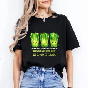 May include: Black t-shirt featuring a graphic of three smiling green chives. The text below reads "LO ÚNICO MÁS PODEROSO QUE EL ODIO, ES EL AMOR." A casual, comfortable tee for everyday wear.