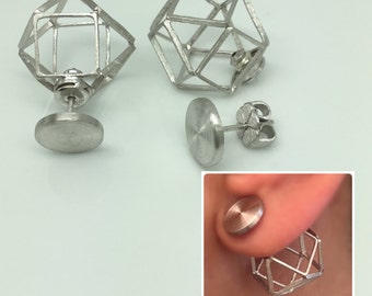 May include: Silver-toned geometric stud earrings. The earrings feature a cage-like design with a post and a round backing. One earring is shown in use, with the backing visible behind the earlobe. The earrings are displayed on a white background.