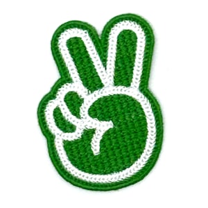 May include: Green peace sign patch with a white outline. The patch is made of a textured fabric.