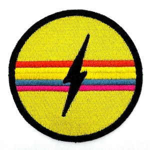 May include: A yellow embroidered patch with a black lightning bolt and four colorful stripes. The stripes are red, blue, pink, and blue.