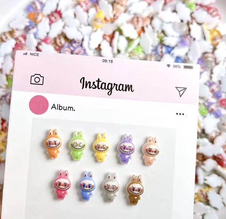 May include: A pink Instagram album display featuring eleven colorful bunny figurines with eerie smiles. The bunnies are in various colors, including orange, green, yellow, purple, pink, blue, gray, and brown. The background is filled with similar figurines.