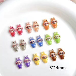 以下が含まれることがあります： カラフルな漫画のウサギのチャームのコレクション。各チャームは約8mm x 14mmで、笑顔の顔とウサギの耳が特徴です。チャームは、赤、オレンジ、ピンク、青、緑、黄色、グレー、茶色、紫など、さまざまな色があります。