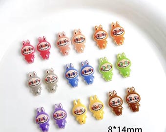 Puede incluir: Una colección de coloridos amuletos de conejito de dibujos animados. Cada amuleto mide aproximadamente 8 mm x 14 mm y presenta una cara sonriente y orejas de conejo. Los amuletos son de varios colores, incluyendo rojo, naranja, rosa, azul, verde, amarillo, gris, marrón y morado.