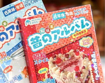 May include: Two Japanese-style sticker albums. One is light blue with stars and text, the other is red with a cake illustration. Both albums have Japanese text and are labeled "Retro Sticker Book".