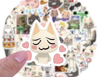 May include: A collection of cat-themed stickers, featuring various cartoon cat designs with different expressions and poses. One sticker is held by a hand, showcasing a white cat with pink hearts. Other stickers include cats with sunglasses and other accessories.