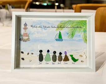 Pode incluir: Uma pintura a aquarela emoldurada que representa uma cena de praia com um farol, uma palmeira, um veleiro e uma família de seis representada por pedras pintadas. O texto "My family walks in different directions sometimes, but we can always find that home" está escrito na pintura.