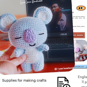 Könnte beinhalten: Ein gehäkeltes Koala-Spielzeug in Blau, Weiß und Lila wird gezeigt. Das Bild enthält eine PDF-Anleitung mit Schritt-für-Schritt-Anweisungen. Der Text auf dem Bild lautet "PDF Crochet Pattern Only - Not Finished Doll" und "Materialien für die Herstellung von Kunsthandwerk."