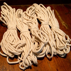 May include: Four spools of natural white cotton rope, tightly wound and ready for crafting projects.