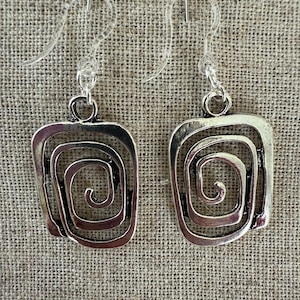 May include: Silver earrings with a square shape and a spiral design. The earrings have a simple hook closure.