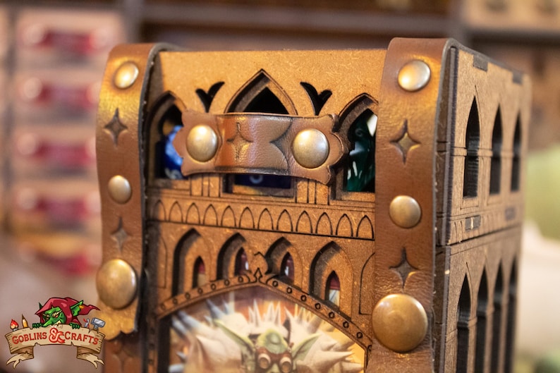 May include: A wooden dice tower with a leather strap and metal accents. The tower is decorated with a gothic design and has a small window on the top. The tower is designed to hold dice and is a great addition to any tabletop game.