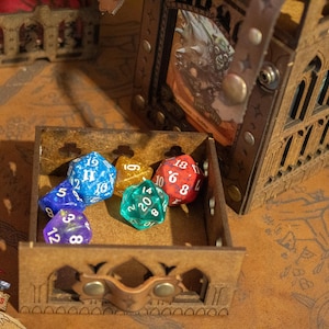 May include: A wooden box with a hinged lid, containing five colorful dice. The dice are blue, green, red, and gold. The box is decorated with a carved design.